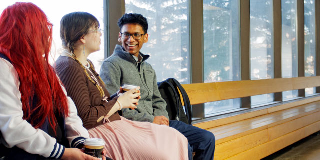 Three students sitting in hallway chatting