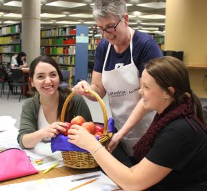 Deb Carnegie, president of the Brandon University Alumni Association, hands out apples as a healthy study snack to second-year nursing students Alex Dubnick (left) and Kiara Hildebrand, on Wednesday evening, Dec. 9, 2015.
