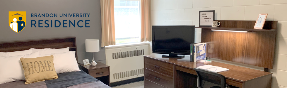 A bed with a pillow that says "home" is next to a desk